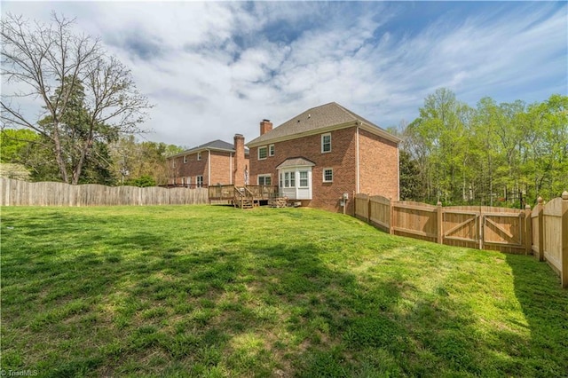 rear view of property with a fenced backyard, a wooden deck, and a yard