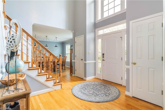 entrance foyer with baseboards, wood finished floors, a towering ceiling, and stairs