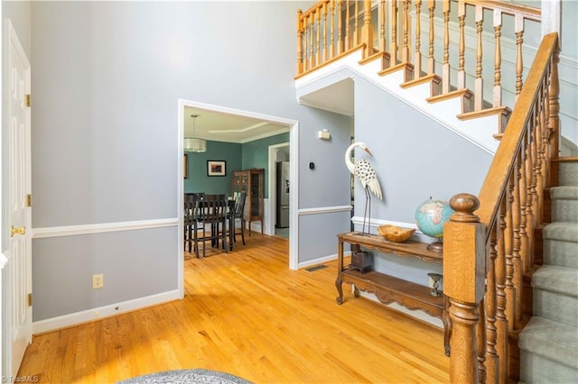 entryway featuring wood finished floors, visible vents, ornamental molding, baseboards, and stairs