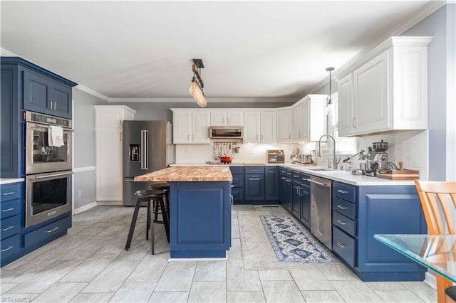 kitchen with stainless steel appliances, ornamental molding, a sink, butcher block counters, and blue cabinetry