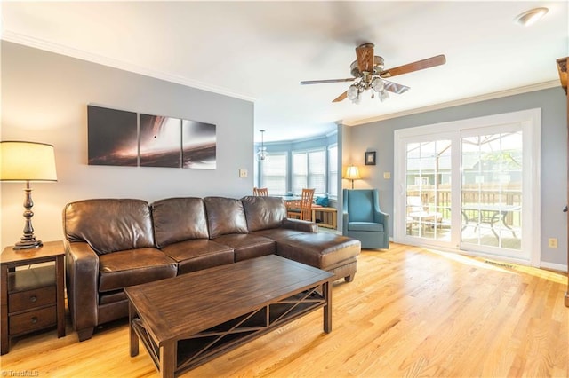 living area featuring ceiling fan, light wood-style flooring, ornamental molding, and plenty of natural light