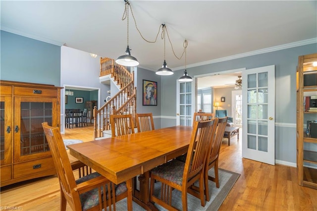 dining space featuring light wood-type flooring, baseboards, stairs, ceiling fan, and ornamental molding