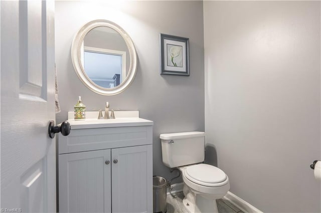 bathroom with baseboards, toilet, and vanity
