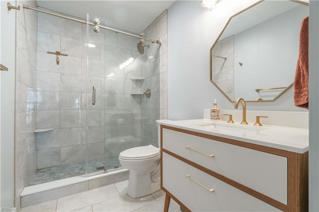 bathroom with a shower stall, toilet, vanity, and tile patterned floors