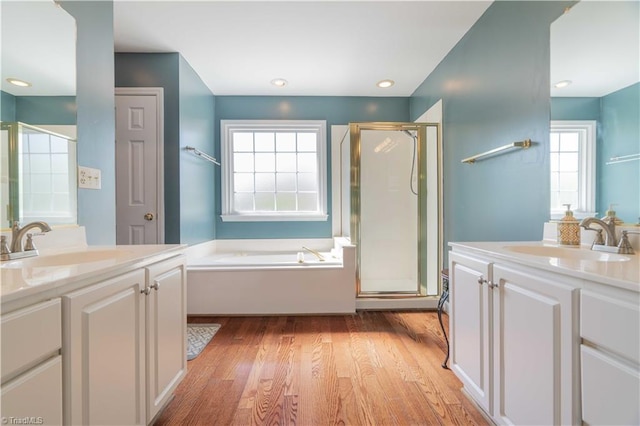 full bathroom featuring a shower stall, wood finished floors, a bath, and a sink
