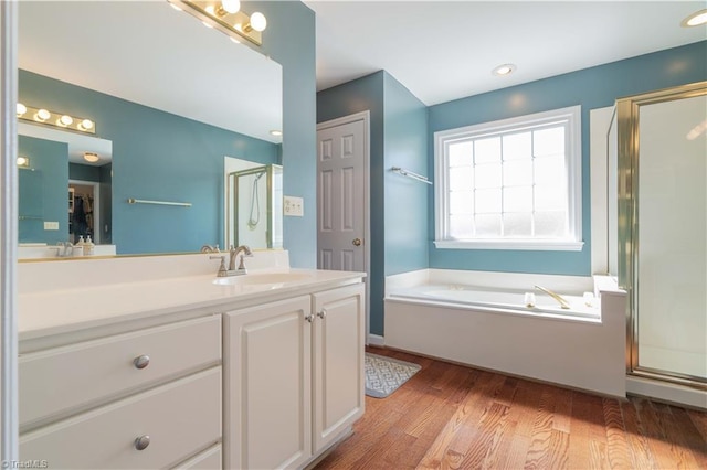 full bath with a bath, vanity, wood finished floors, and a shower stall