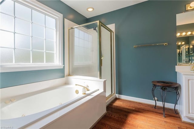 full bath featuring wood finished floors, a jetted tub, vanity, and a stall shower