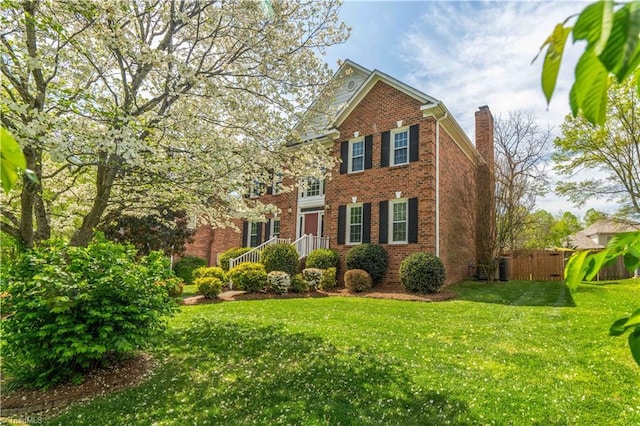 exterior space with fence, a front lawn, brick siding, and a chimney