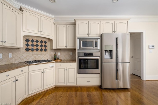5000 Casting Way, Greensboro, NC 27455 - kitchen featuring appliances with stainless steel finishes, cream cabinets, dark wood-type flooring, backsplash, and crown molding