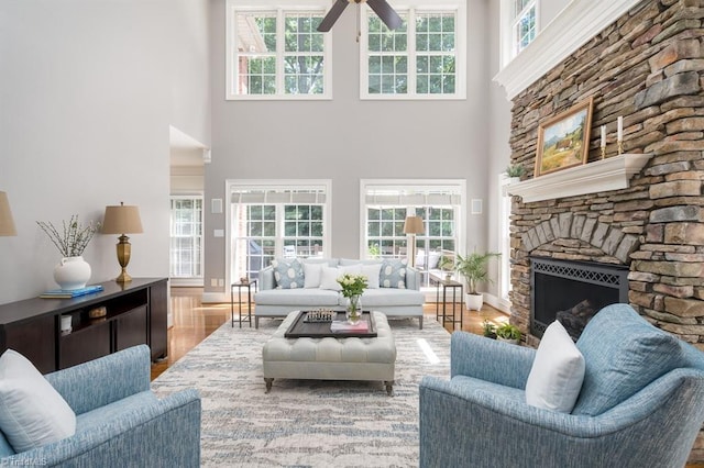 5000 Casting Way, Greensboro, NC 27455 - living room featuring a ceiling fan, a high ceiling, wood finished floors, a stone fireplace, and plenty of natural light