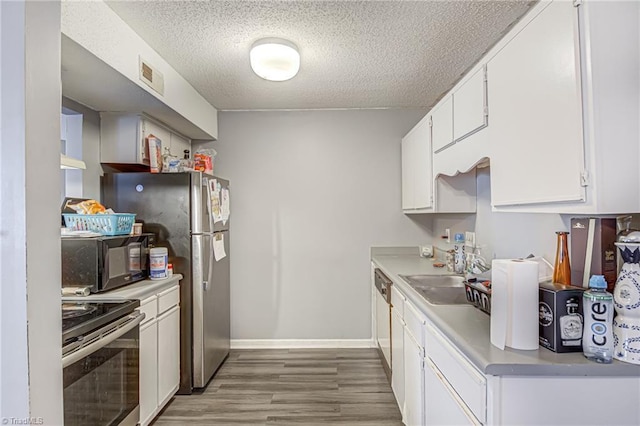 kitchen featuring stove, white cabinets, light hardwood / wood-style flooring, stainless steel dishwasher, and sink