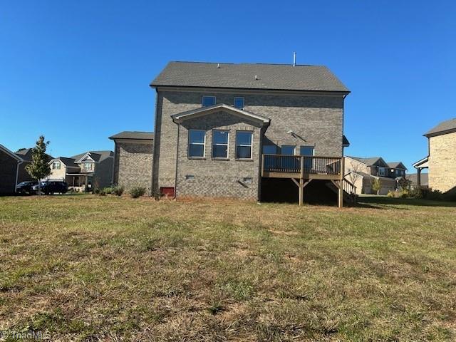 back of house featuring a wooden deck and a lawn