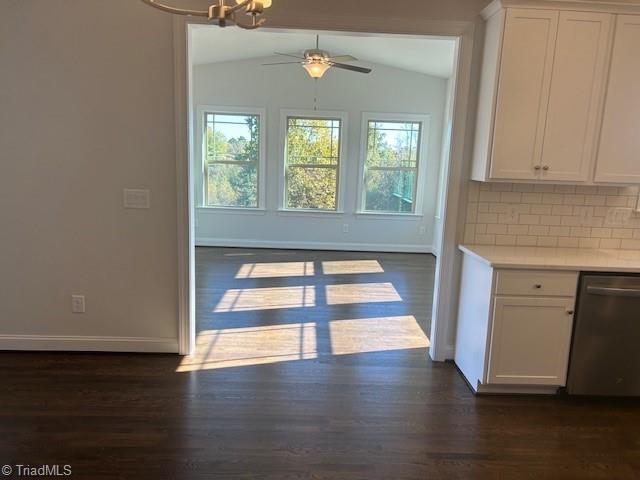 unfurnished dining area featuring ceiling fan, dark hardwood / wood-style floors, and vaulted ceiling