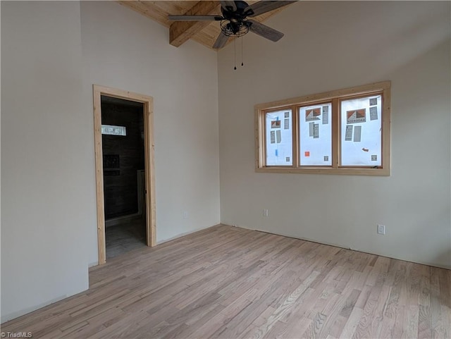 spare room with light wood-type flooring, a ceiling fan, and beamed ceiling