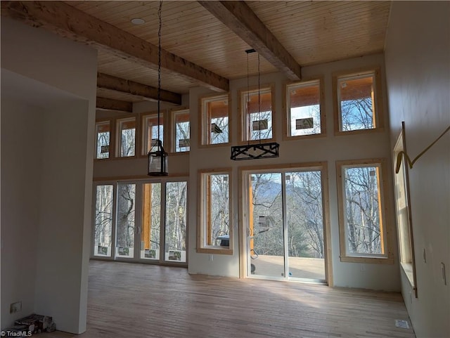 interior space featuring a towering ceiling, beam ceiling, wood finished floors, and wood ceiling