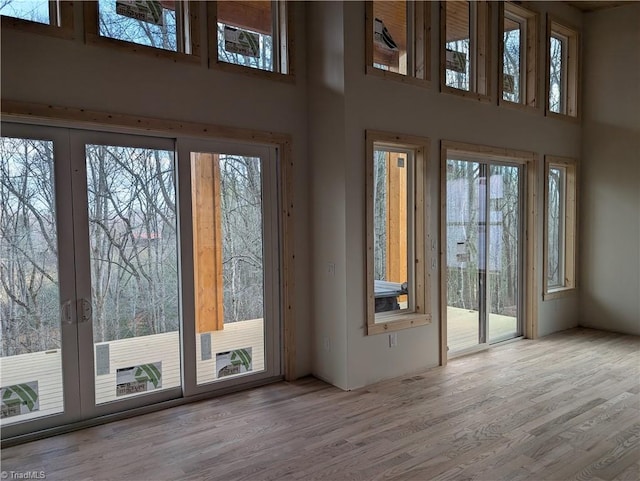 doorway to outside with french doors, a towering ceiling, and wood finished floors