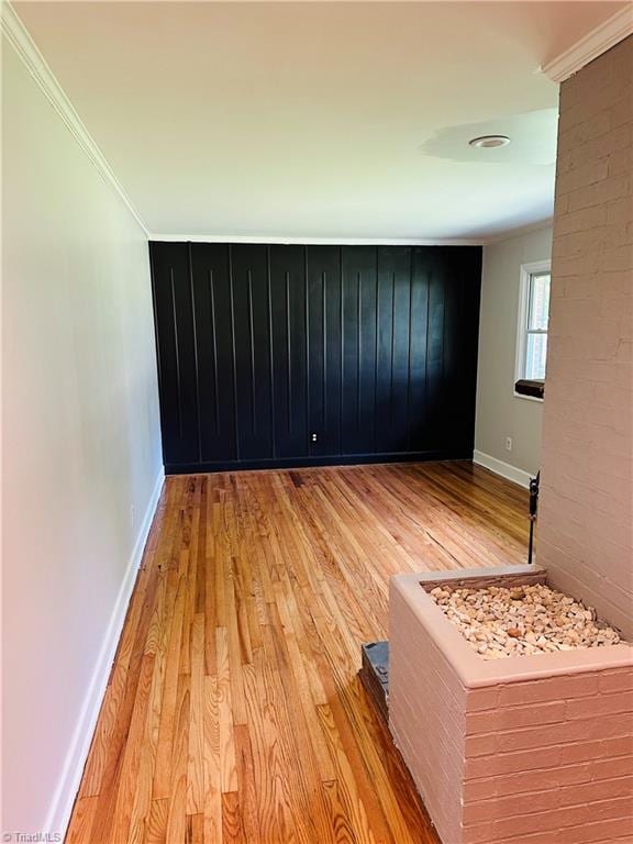 empty room featuring light wood-type flooring and crown molding