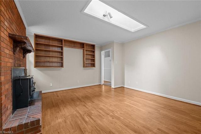 2206 Revolan Dr, Greensboro, NC 27407 - unfurnished living room with light wood-type flooring, a wood stove, and ornamental molding
