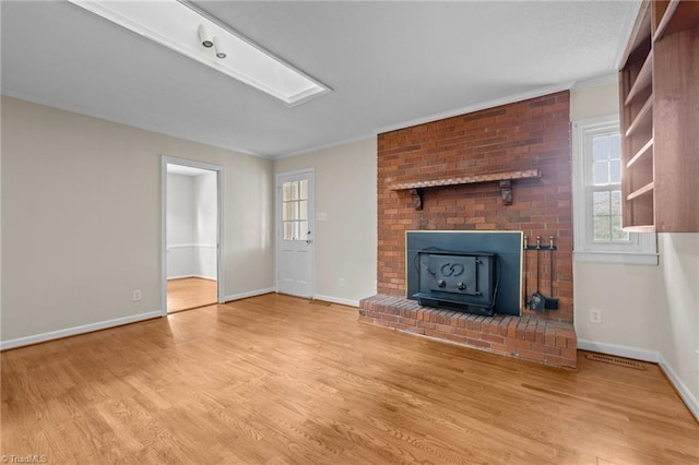 2206 Revolan Dr, Greensboro, NC 27407 - unfurnished living room with wood finished floors, crown molding, and a wood stove