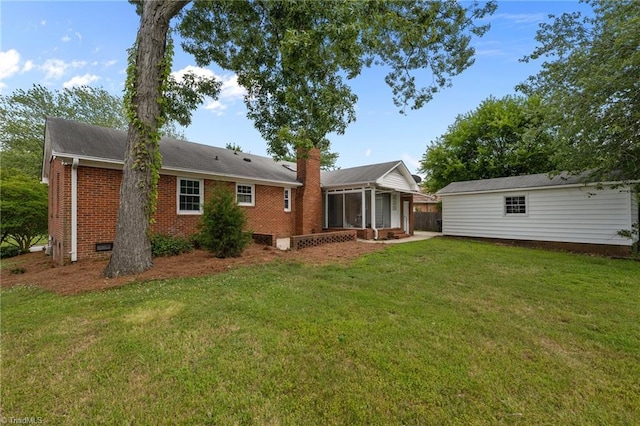 2206 Revolan Dr, Greensboro, NC 27407 - back of house featuring a sunroom, brick siding, a lawn, and a chimney