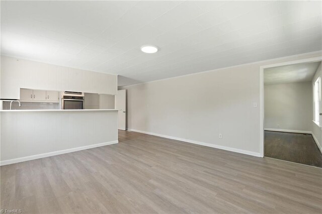 1616 Sanford Dr, Winston-Salem, NC 27105 - unfurnished living room with baseboards, a sink, and wood finished floors
