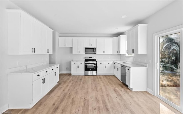 kitchen featuring appliances with stainless steel finishes, a healthy amount of sunlight, white cabinets, and sink