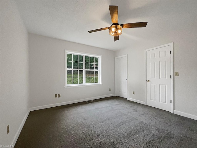 interior space with a textured ceiling, dark colored carpet, and ceiling fan