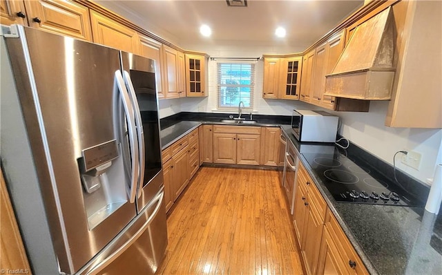 kitchen featuring black electric cooktop, premium range hood, stainless steel fridge with ice dispenser, sink, and light hardwood / wood-style floors