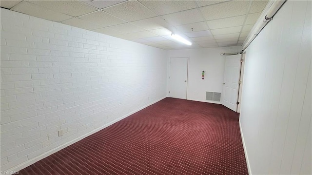 carpeted spare room featuring a drop ceiling