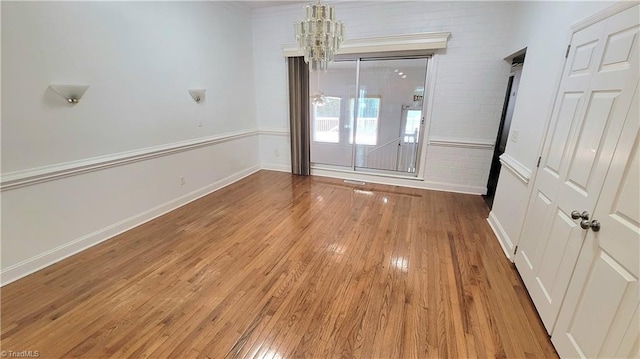 empty room with a notable chandelier and hardwood / wood-style floors