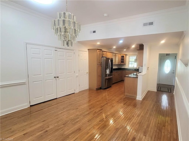 kitchen with a notable chandelier, ornamental molding, stainless steel fridge with ice dispenser, and hardwood / wood-style floors