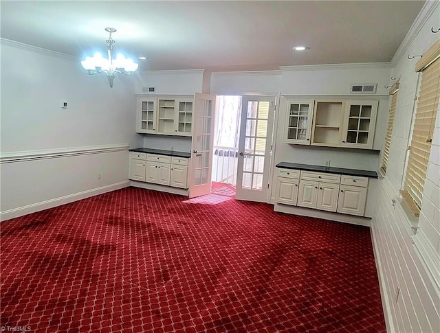 interior space featuring ornamental molding, dark colored carpet, and a chandelier