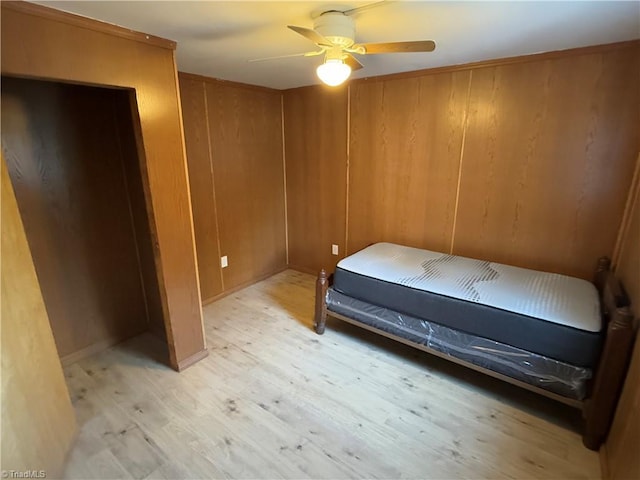 bedroom with wood walls, ceiling fan, and light hardwood / wood-style floors