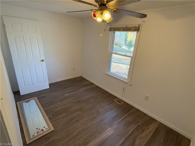 spare room with crown molding, ceiling fan, and dark wood-type flooring