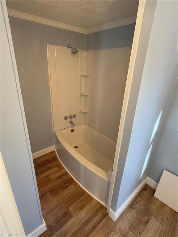 bathroom featuring hardwood / wood-style floors, tiled shower / bath combo, ornamental molding, and a textured ceiling