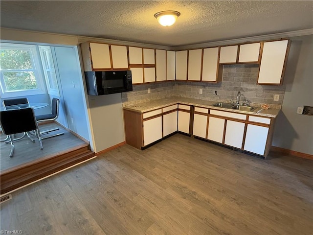 kitchen with white cabinets, sink, light hardwood / wood-style flooring, decorative backsplash, and a textured ceiling