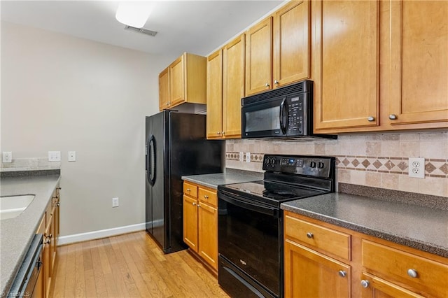 kitchen featuring baseboards, light wood finished floors, black appliances, dark countertops, and backsplash