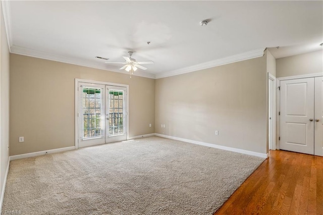 carpeted empty room with visible vents, baseboards, crown molding, and ceiling fan