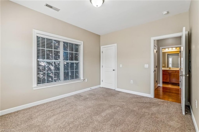 unfurnished bedroom with visible vents, baseboards, carpet floors, multiple windows, and a sink