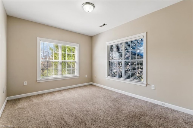 carpeted spare room with visible vents and baseboards