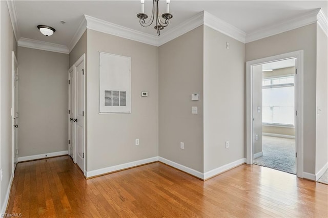 entrance foyer with a chandelier, crown molding, light wood-type flooring, and baseboards