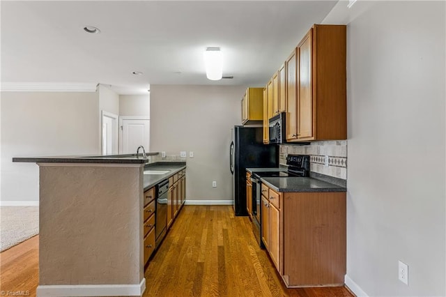 kitchen with a peninsula, a sink, black microwave, range with electric stovetop, and tasteful backsplash