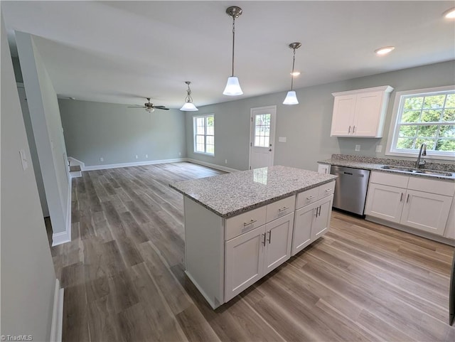 kitchen featuring a sink, wood finished floors, white cabinetry, dishwasher, and hanging light fixtures