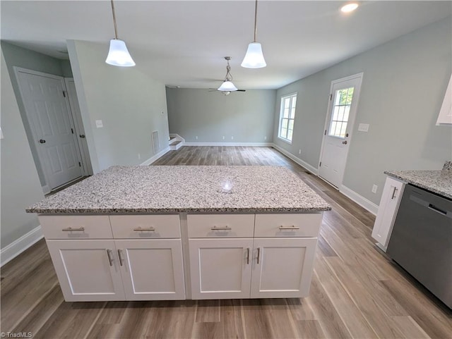 kitchen featuring light wood-style flooring, stainless steel dishwasher, pendant lighting, and white cabinets