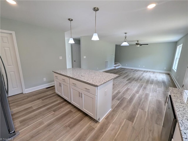 kitchen featuring light stone counters, hanging light fixtures, light hardwood / wood-style floors, and white cabinets