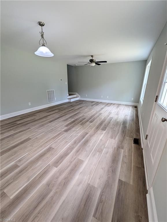 unfurnished living room featuring ceiling fan, visible vents, baseboards, and wood finished floors