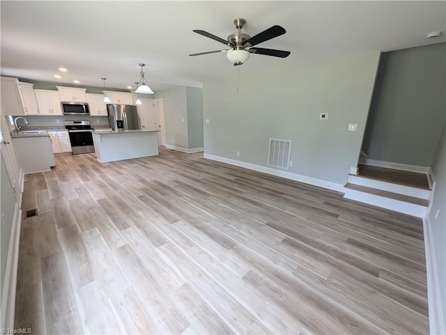 unfurnished living room with baseboards, visible vents, ceiling fan, a sink, and light wood-style floors