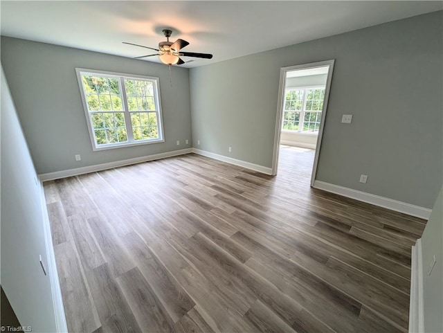 unfurnished room with dark wood-style floors, baseboards, and ceiling fan