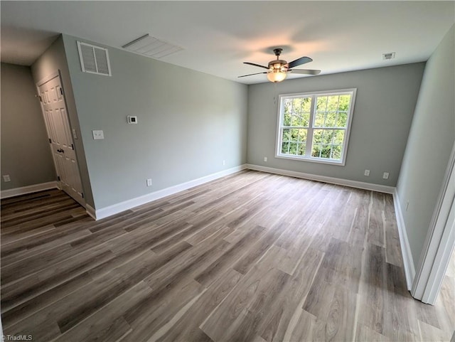 unfurnished room with wood finished floors, visible vents, and baseboards