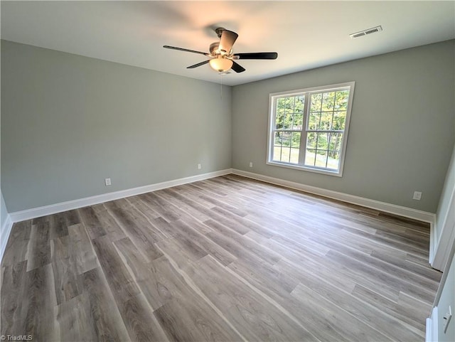 unfurnished room featuring visible vents, baseboards, wood finished floors, and a ceiling fan
